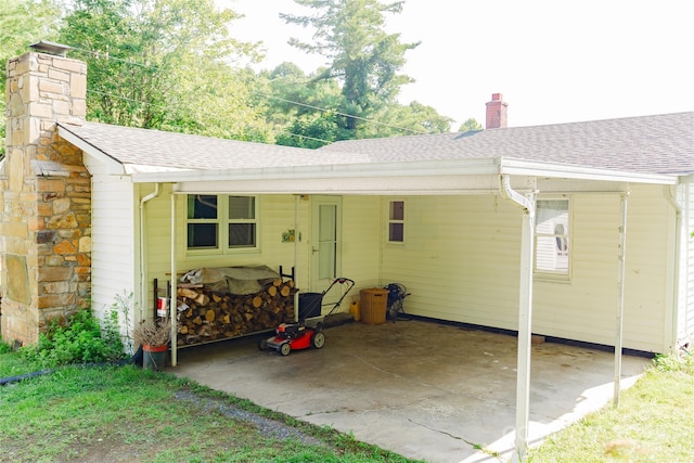 exterior space featuring a chimney, an attached carport, and roof with shingles