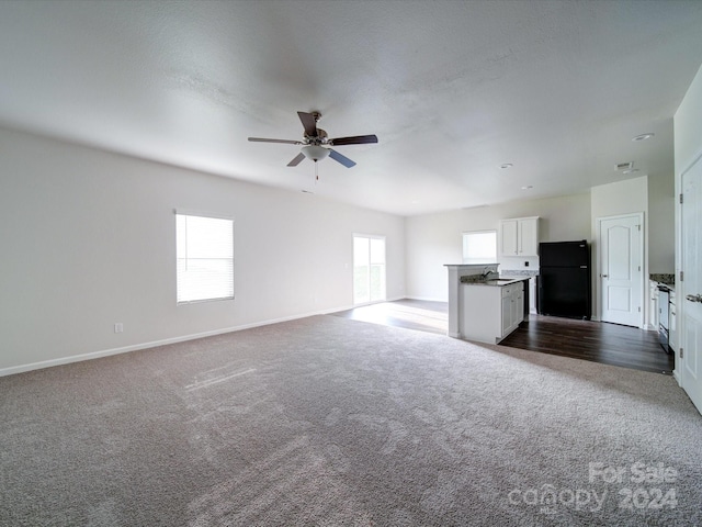 unfurnished living room featuring ceiling fan, sink, and dark colored carpet