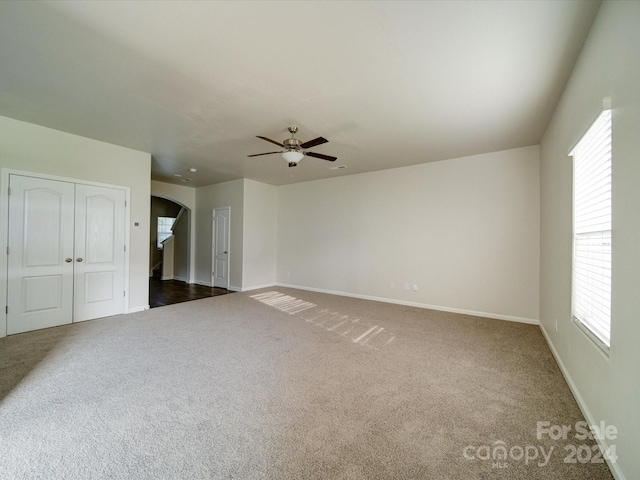 interior space featuring ceiling fan, carpet flooring, and multiple windows