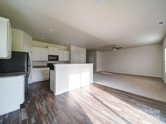 kitchen with ceiling fan, white cabinetry, dark wood-type flooring, black appliances, and a kitchen island