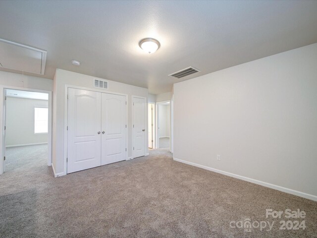 unfurnished bedroom featuring light carpet and a closet