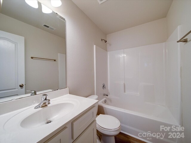 full bathroom featuring wood-type flooring, washtub / shower combination, vanity, and toilet