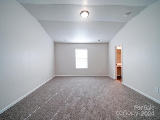 unfurnished room featuring lofted ceiling and carpet flooring