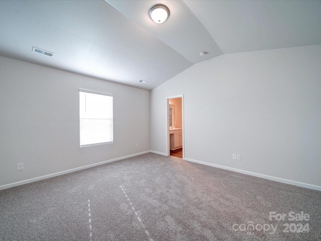 spare room with carpet flooring and vaulted ceiling