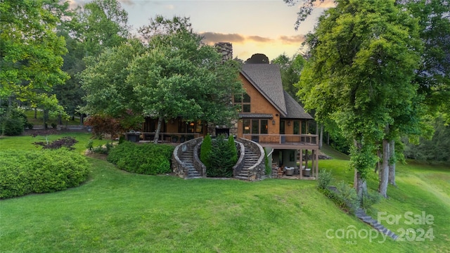 back house at dusk featuring a lawn