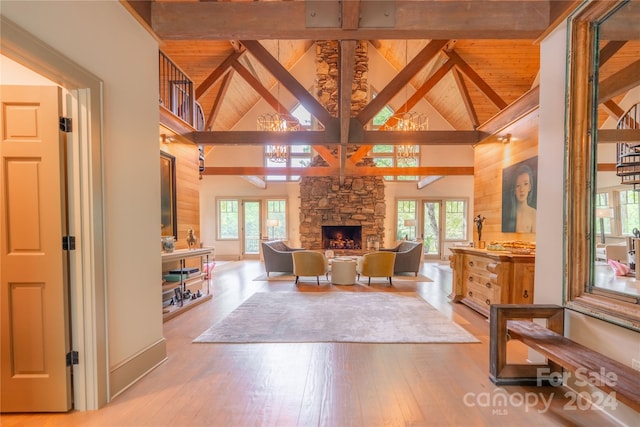 living room featuring a stone fireplace, beamed ceiling, light wood-type flooring, and high vaulted ceiling