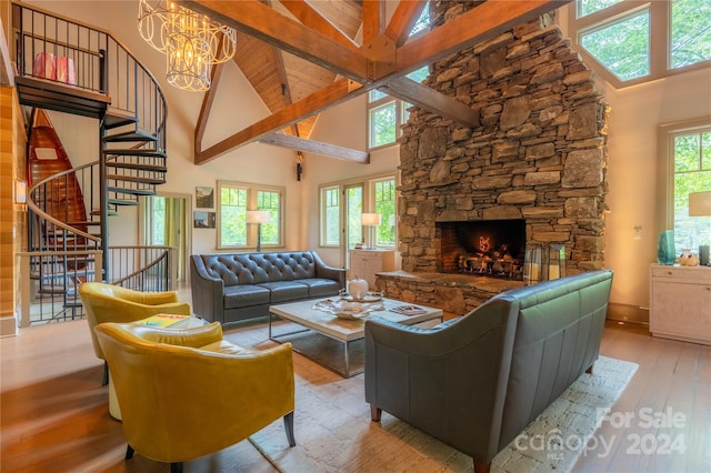 living room with light hardwood / wood-style flooring, an inviting chandelier, a stone fireplace, and high vaulted ceiling