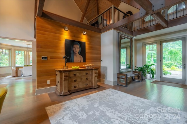 bedroom featuring hardwood / wood-style floors, wooden walls, and a high ceiling