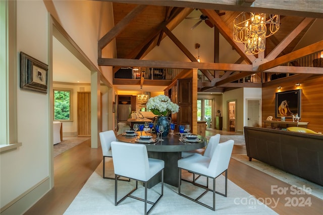 dining room with beam ceiling, ceiling fan with notable chandelier, light hardwood / wood-style flooring, and high vaulted ceiling