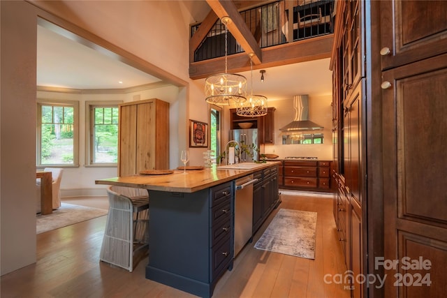 kitchen with light wood-type flooring, a center island, dishwasher, wall chimney exhaust hood, and sink