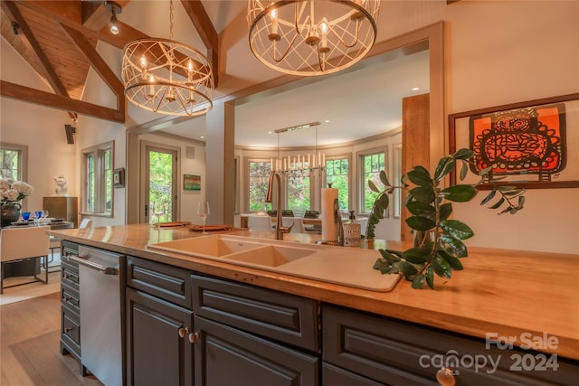 kitchen with light hardwood / wood-style flooring, sink, stainless steel dishwasher, beam ceiling, and a chandelier