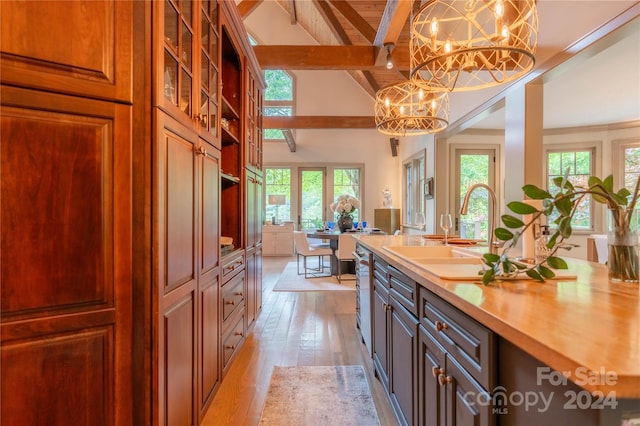 kitchen with an inviting chandelier, sink, decorative light fixtures, stainless steel dishwasher, and light wood-type flooring