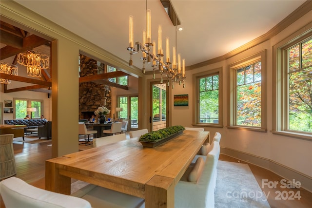 dining space with a fireplace, a chandelier, hardwood / wood-style flooring, and a healthy amount of sunlight