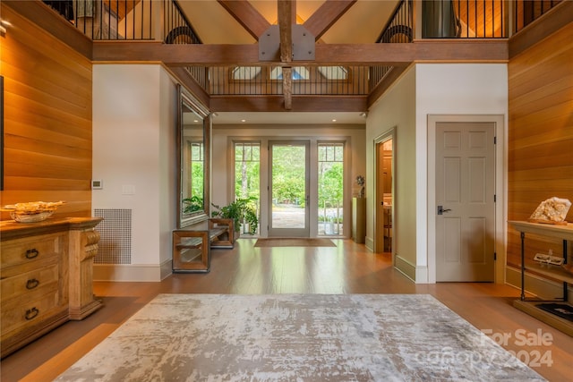 bedroom with wood walls, wood-type flooring, and a towering ceiling