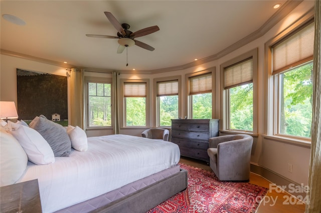 bedroom featuring hardwood / wood-style flooring, ornamental molding, multiple windows, and ceiling fan