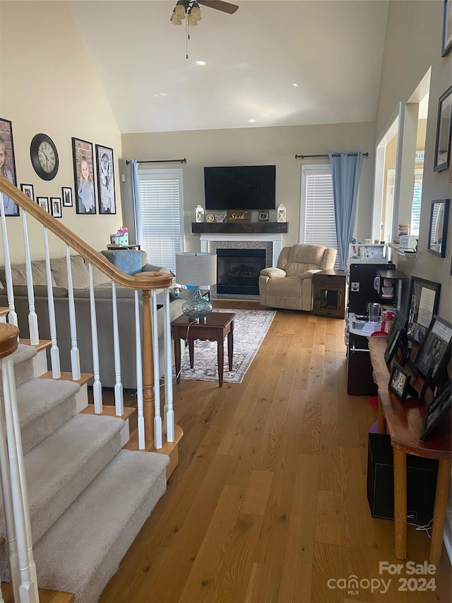 living room featuring high vaulted ceiling, a tiled fireplace, ceiling fan, and hardwood / wood-style floors