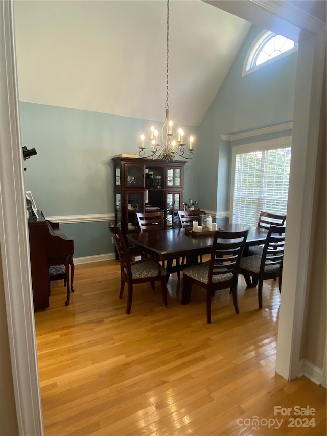 dining area with light hardwood / wood-style flooring, high vaulted ceiling, and a chandelier