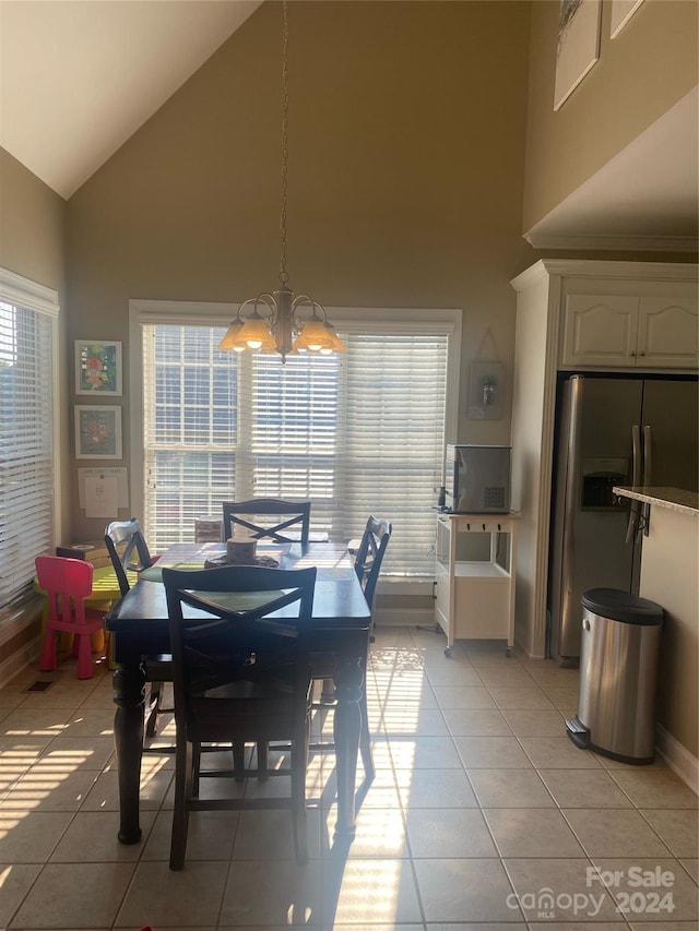 dining space with a notable chandelier, a wealth of natural light, light tile patterned floors, and high vaulted ceiling