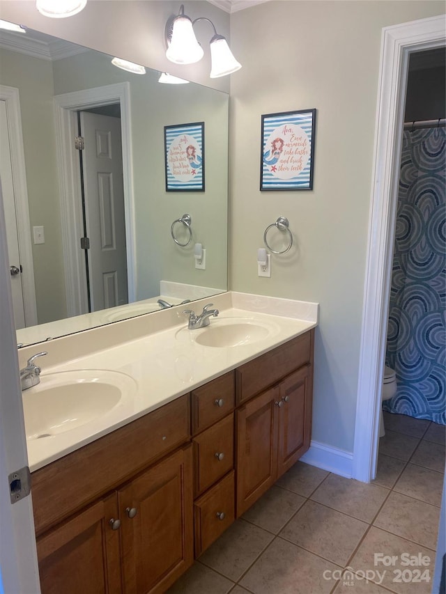 bathroom with tile patterned floors, ornamental molding, toilet, and dual bowl vanity