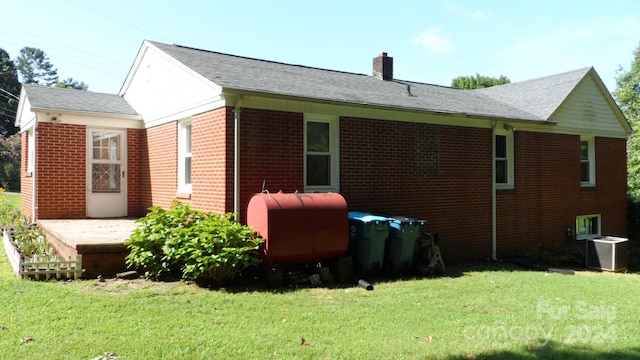 back of property with central AC and a lawn