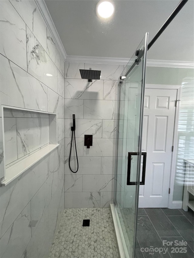 bathroom with a shower with shower door and ornamental molding