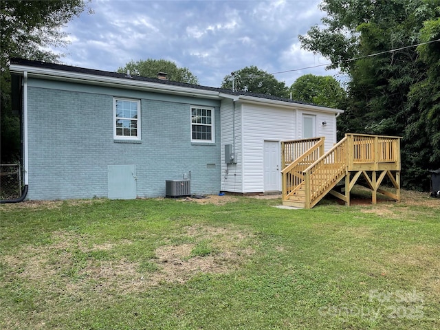 rear view of house with central AC, a deck, and a lawn