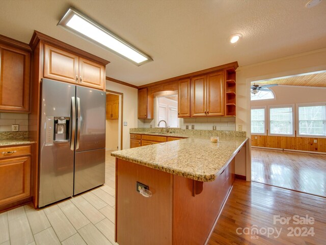 kitchen featuring kitchen peninsula, lofted ceiling, ceiling fan, a breakfast bar, and stainless steel refrigerator with ice dispenser