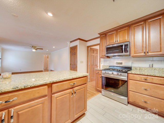 kitchen featuring light stone countertops, backsplash, ceiling fan, stainless steel appliances, and light hardwood / wood-style flooring