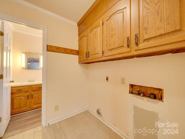 laundry area featuring sink, cabinets, hookup for a washing machine, crown molding, and electric dryer hookup