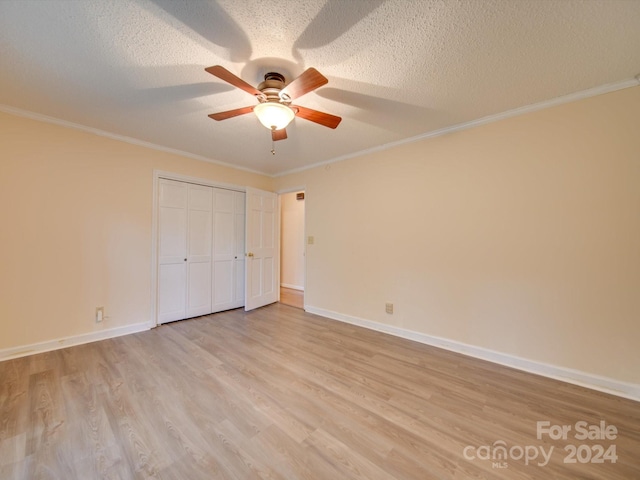 unfurnished bedroom featuring a closet, light hardwood / wood-style flooring, ornamental molding, a textured ceiling, and ceiling fan