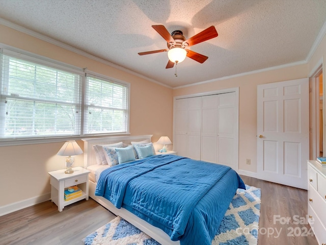 bedroom featuring a textured ceiling, a closet, light hardwood / wood-style floors, ceiling fan, and ornamental molding