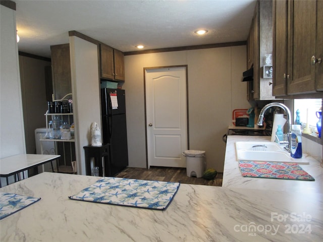 kitchen with dark wood-type flooring, crown molding, sink, and black refrigerator