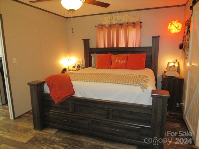 bedroom with a barn door, ceiling fan, and hardwood / wood-style floors