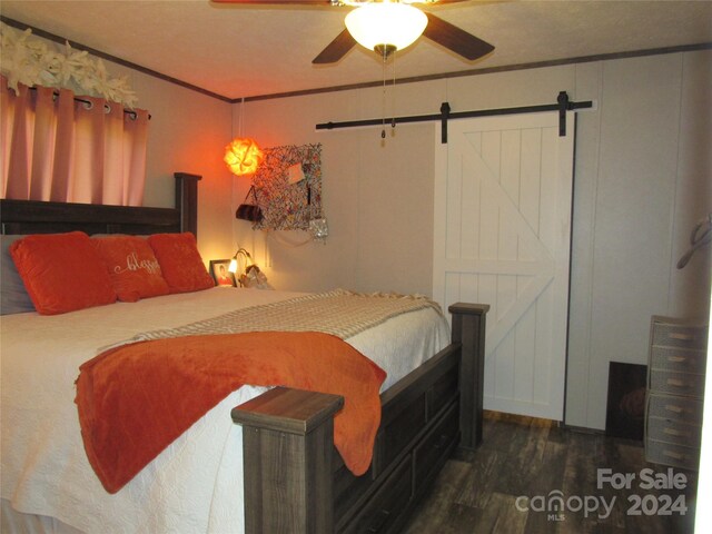 bedroom with ceiling fan, crown molding, dark hardwood / wood-style flooring, and a barn door