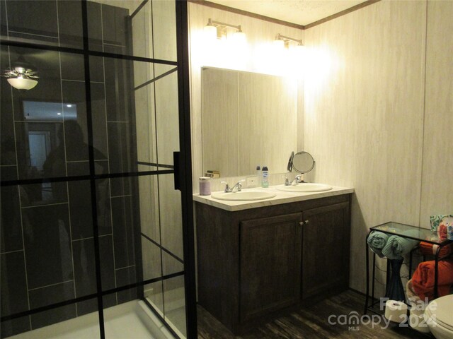 bathroom featuring hardwood / wood-style flooring, double vanity, crown molding, an enclosed shower, and toilet