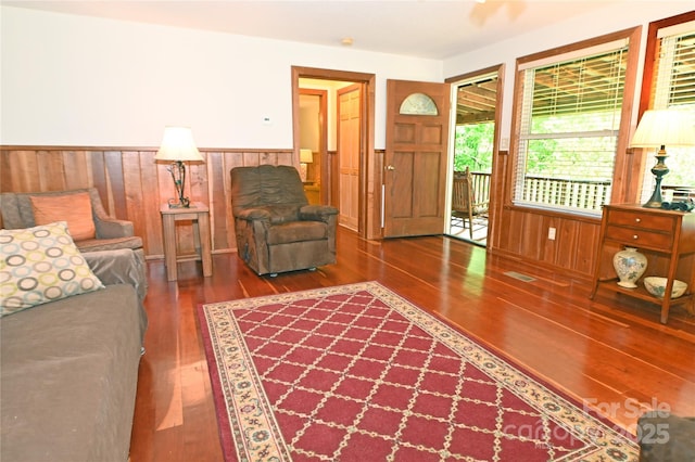 living room with dark hardwood / wood-style flooring and wooden walls