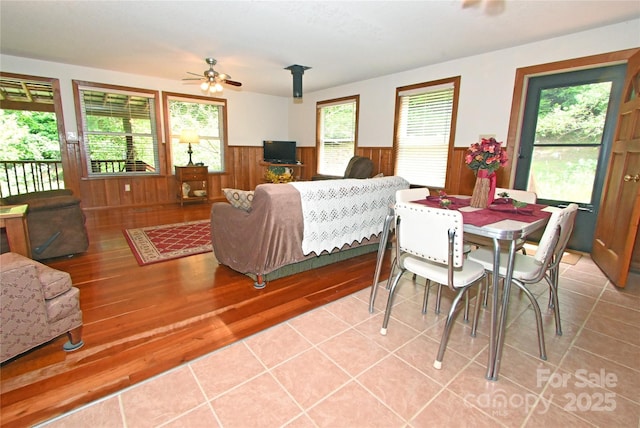 tiled dining room featuring ceiling fan and wood walls