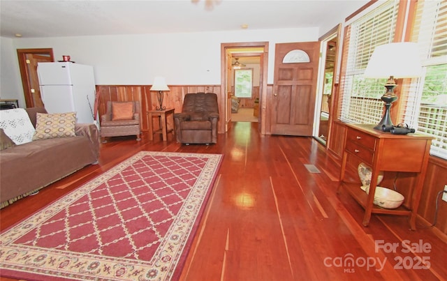 living room with hardwood / wood-style flooring, plenty of natural light, and wood walls