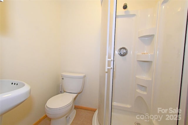 bathroom featuring tile patterned floors, toilet, a shower with door, and sink