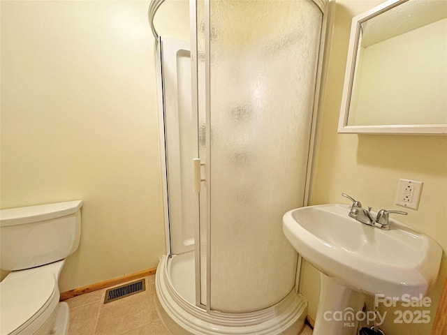 bathroom with tile patterned flooring, toilet, a shower with door, and sink