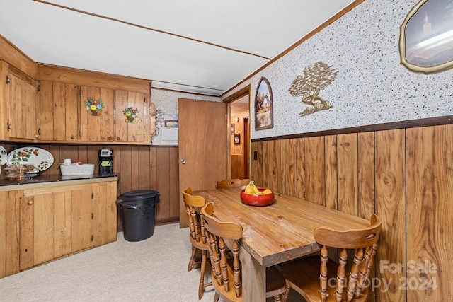 dining room with wood walls and light colored carpet