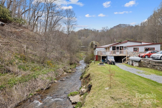 view of front of home featuring a front lawn and a deck with water view