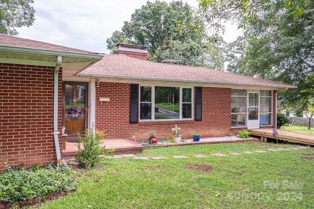 single story home featuring a deck and a front lawn