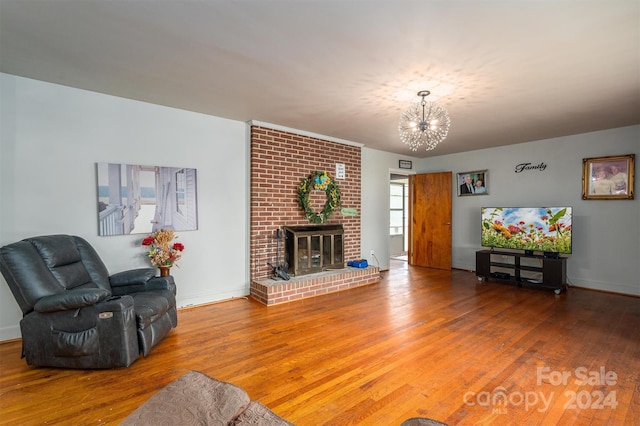 living room with hardwood / wood-style flooring, a brick fireplace, and a notable chandelier