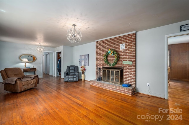 living room featuring wood-type flooring, a fireplace, and a chandelier