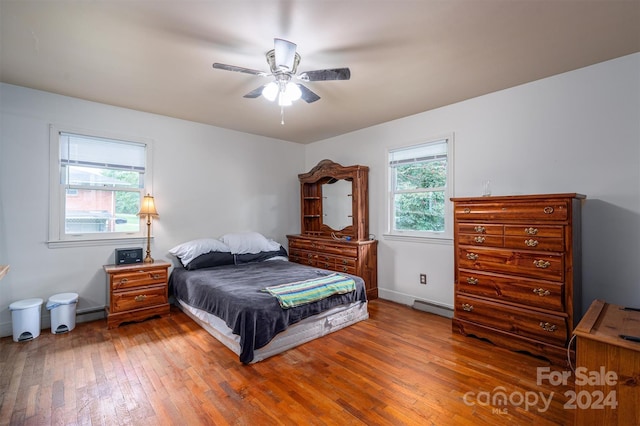 bedroom featuring baseboard heating, ceiling fan, and wood-type flooring