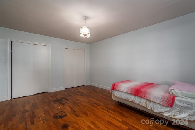 bedroom with two closets and dark hardwood / wood-style floors