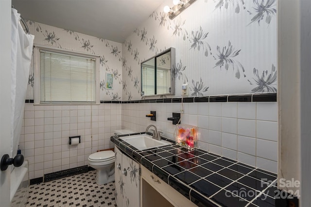 bathroom with tile walls, vanity, tile patterned floors, and toilet