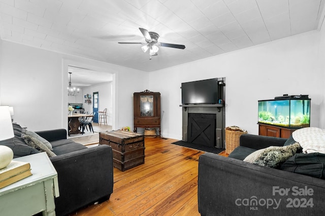 living room with ceiling fan with notable chandelier, light hardwood / wood-style flooring, and ornamental molding