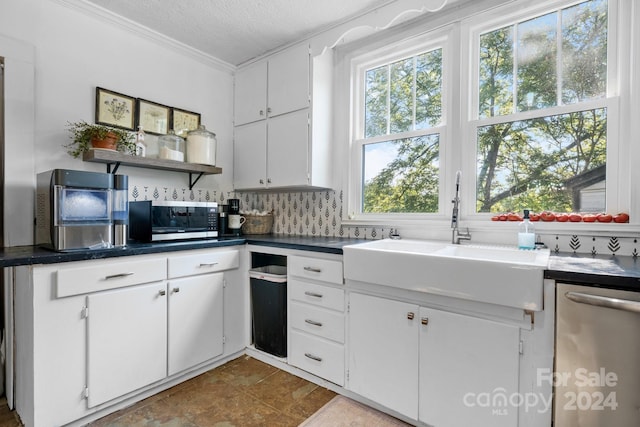 kitchen with sink, appliances with stainless steel finishes, white cabinetry, ornamental molding, and a textured ceiling